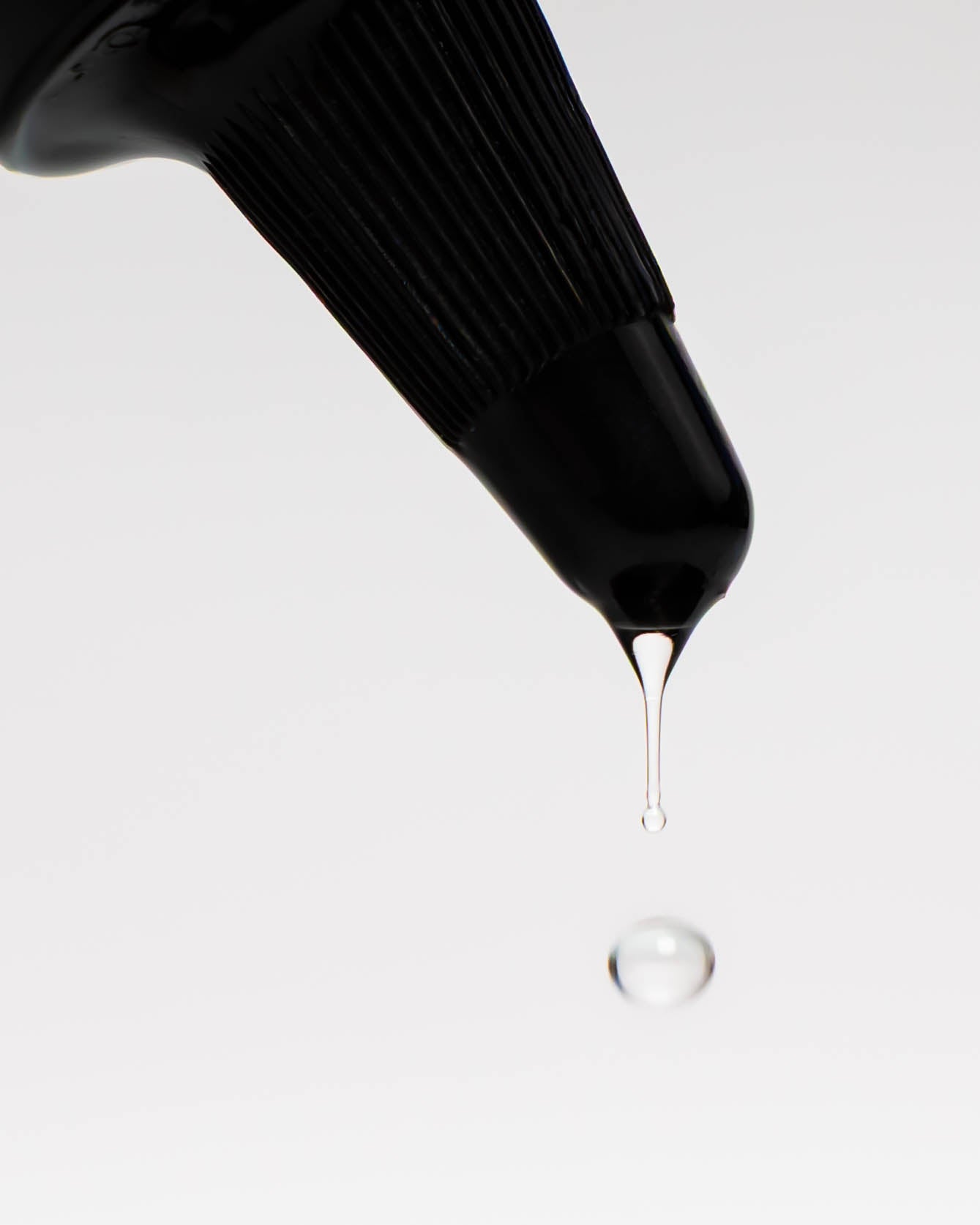 Ein Tropfen, der aus der Tülle der Haarfluidflasche tropft.