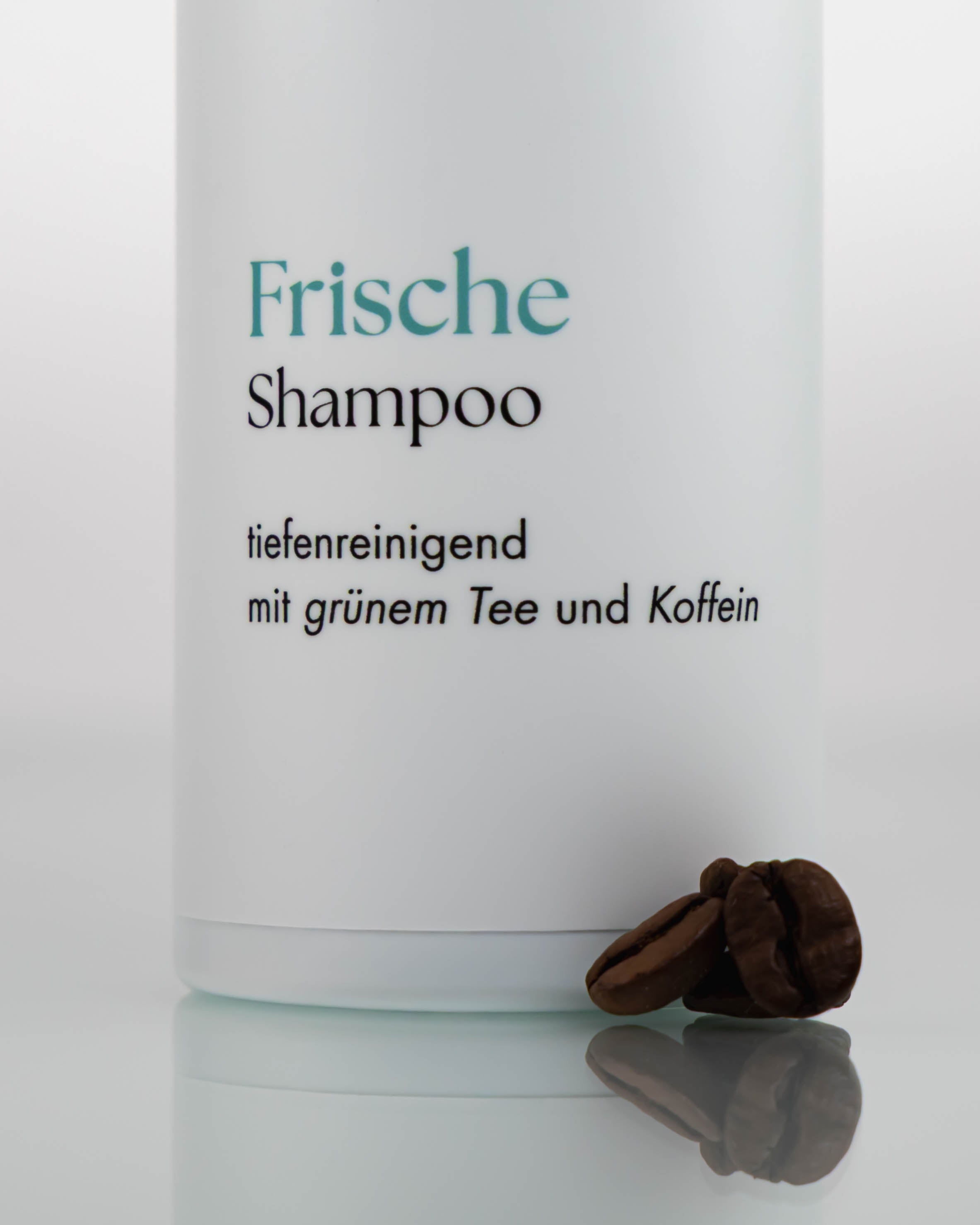 Flasche Frischeshampoo, davor liegen Kaffeebohnen.
