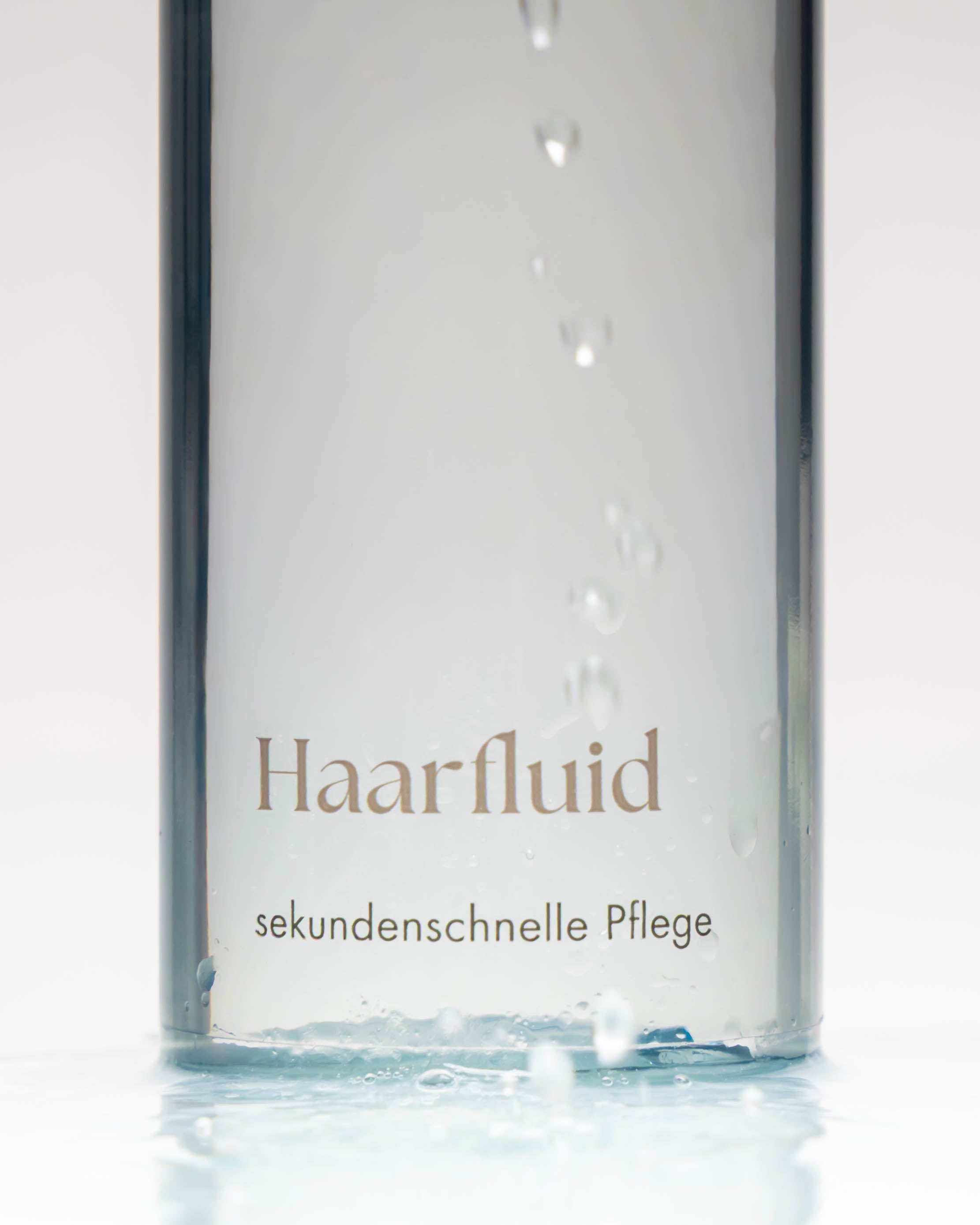Flasche Haarfluid und davor Tropfen.