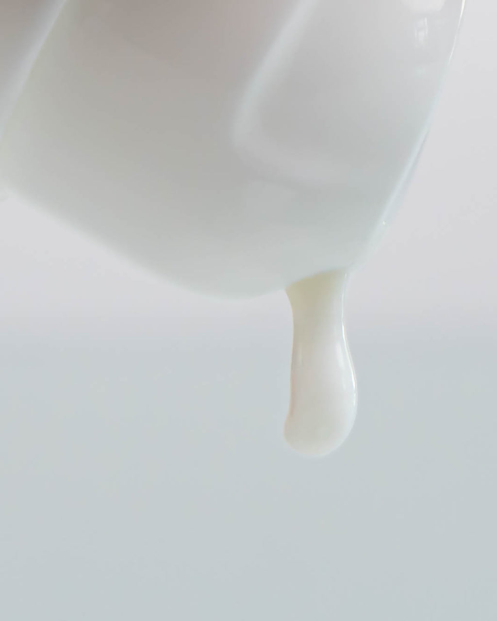 Der Kopf einer Flasche Lockencreme, aus der ein Tropfen Creme tropft.